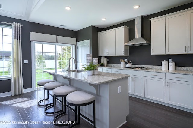 kitchen with a sink, wall chimney exhaust hood, baseboards, visible vents, and dark wood-style floors