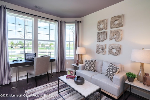 living room with baseboards, visible vents, and wood finished floors