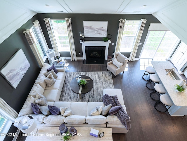 living area featuring a tiled fireplace, a wealth of natural light, and wood finished floors