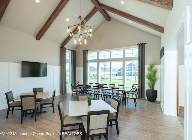 dining space with beam ceiling, wood finished floors, high vaulted ceiling, an inviting chandelier, and recessed lighting