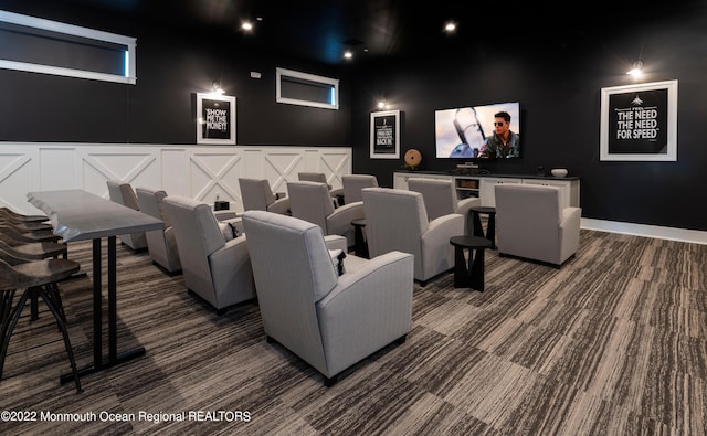 home theater featuring baseboards, carpet, and a decorative wall
