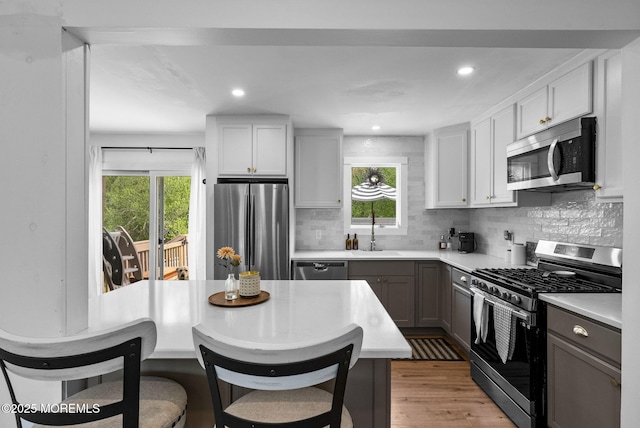 113 Darien Rd, Howell, NJ 07731 - kitchen with appliances with stainless steel finishes, a sink, backsplash, light countertops, and light wood-type flooring