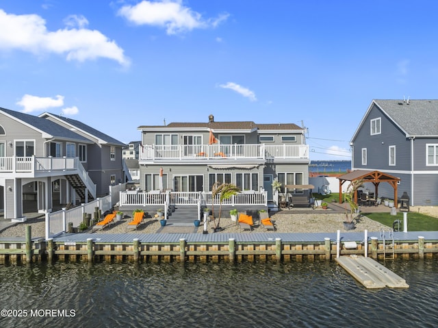 rear view of property with fence, a gazebo, a deck with water view, a balcony, and a patio