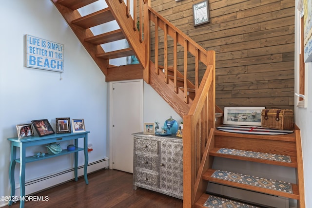 stairs with wood walls, a baseboard heating unit, and wood finished floors