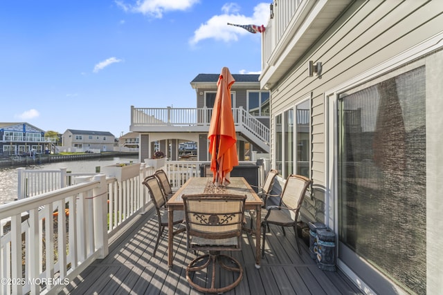 wooden terrace featuring a water view and outdoor dining area