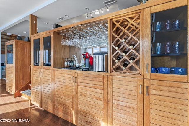 wine area featuring wet bar, visible vents, a sink, and wood finished floors