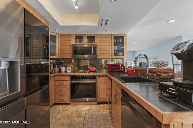 kitchen with decorative backsplash, tile countertops, visible vents, appliances with stainless steel finishes, and a sink