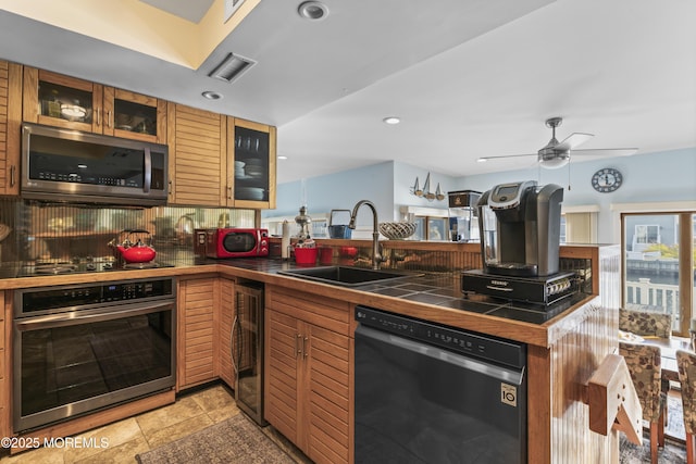 kitchen featuring visible vents, appliances with stainless steel finishes, a sink, a peninsula, and beverage cooler