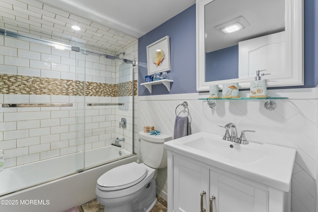 full bathroom with vanity, wainscoting, combined bath / shower with glass door, and toilet