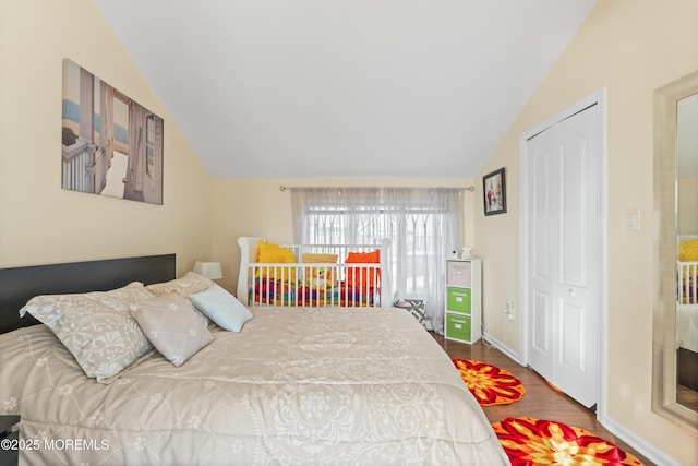 bedroom featuring baseboards, wood finished floors, and vaulted ceiling