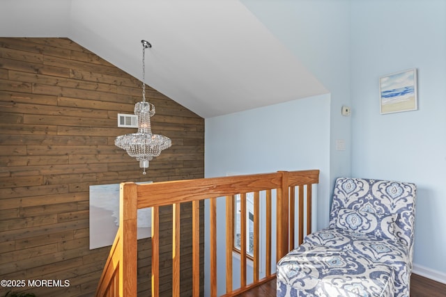 living area with visible vents, lofted ceiling, wooden walls, dark wood-style floors, and a chandelier