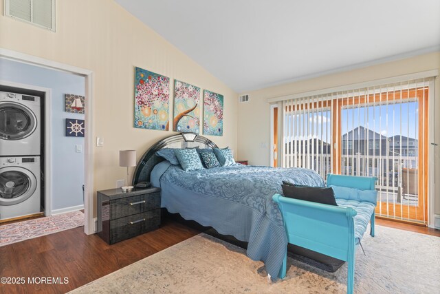 bedroom featuring stacked washing maching and dryer, lofted ceiling, dark wood finished floors, and visible vents