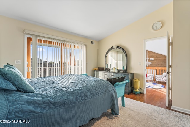 bedroom featuring access to outside, baseboards, wood finished floors, vaulted ceiling, and visible vents