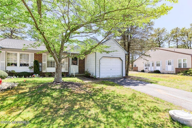 ranch-style home with brick siding, an attached garage, a front lawn, and aphalt driveway