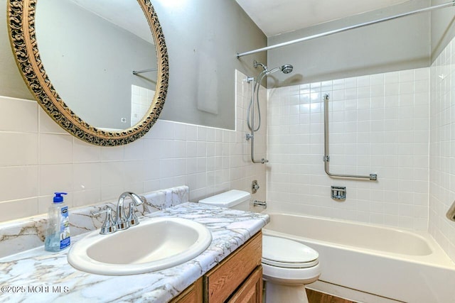 bathroom featuring vanity, toilet, tile walls, backsplash, and shower / washtub combination