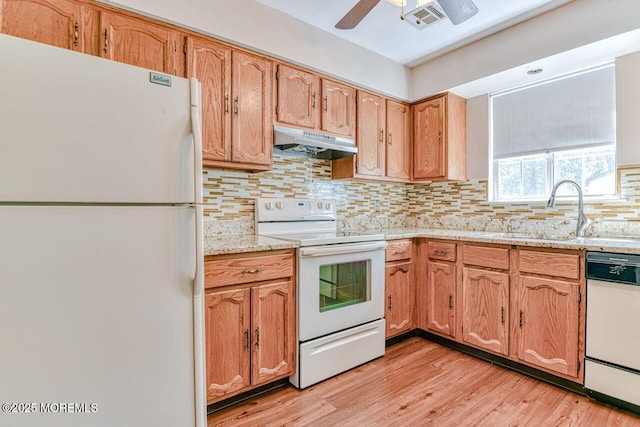 kitchen featuring visible vents, white appliances, under cabinet range hood, tasteful backsplash, and a sink