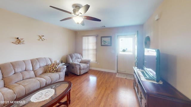 living area with baseboards, a ceiling fan, light wood-type flooring, and visible vents