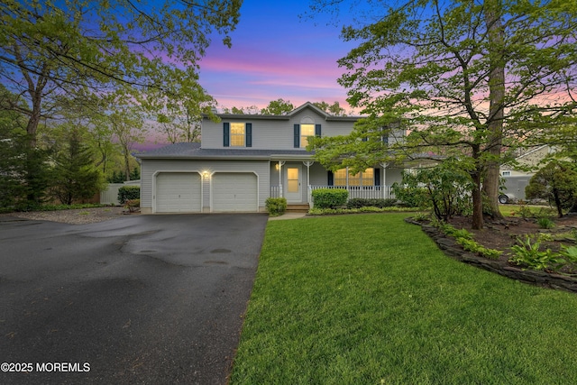 traditional home featuring a lawn, a porch, aphalt driveway, and an attached garage