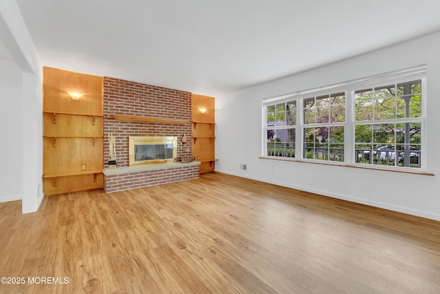 unfurnished living room featuring baseboards, wood finished floors, and a fireplace
