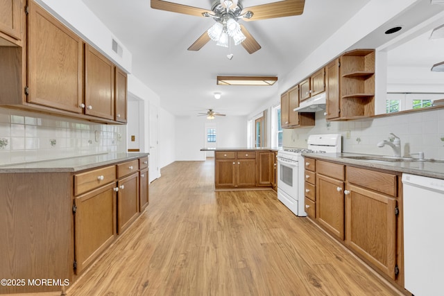 kitchen with a sink, a peninsula, white appliances, under cabinet range hood, and ceiling fan