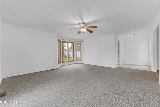 empty room featuring carpet, visible vents, baseboards, and ceiling fan