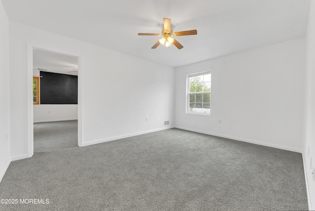 carpeted spare room with visible vents, baseboards, and ceiling fan