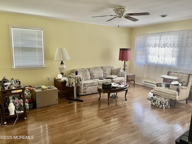 living room featuring a ceiling fan, a baseboard heating unit, and hardwood / wood-style floors
