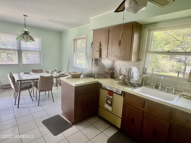 kitchen featuring dishwashing machine, light countertops, a sink, and a healthy amount of sunlight