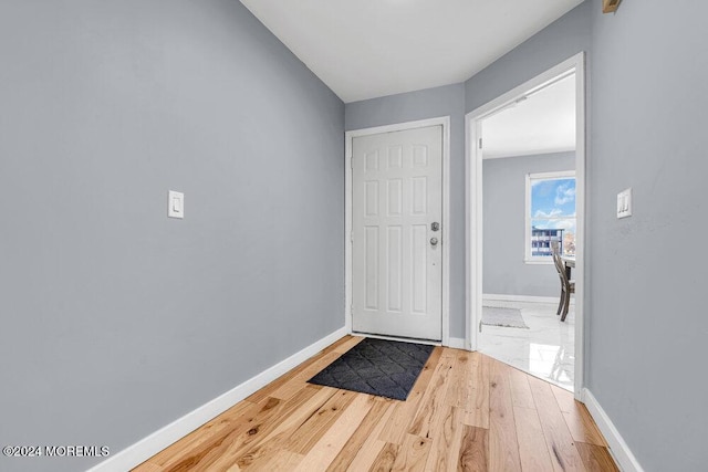 doorway featuring baseboards and wood finished floors