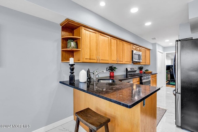 kitchen featuring marble finish floor, a peninsula, a breakfast bar area, a sink, and appliances with stainless steel finishes