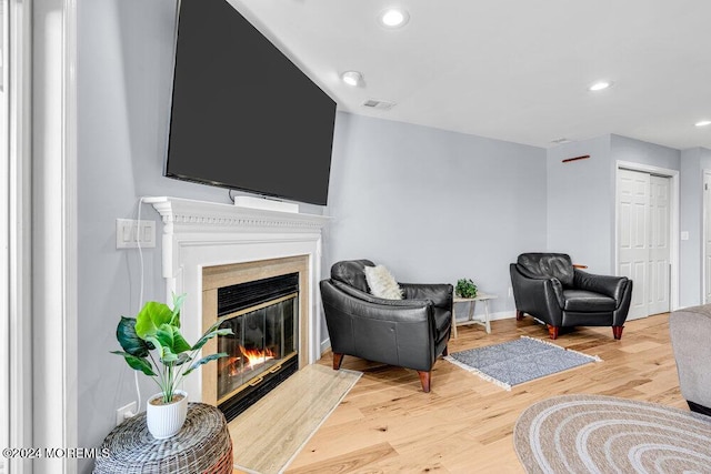 living room featuring visible vents, a glass covered fireplace, wood finished floors, baseboards, and recessed lighting