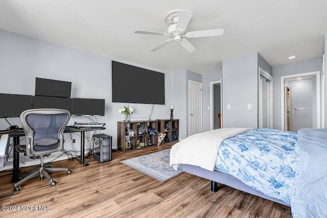 bedroom featuring ceiling fan, multiple closets, and wood finished floors