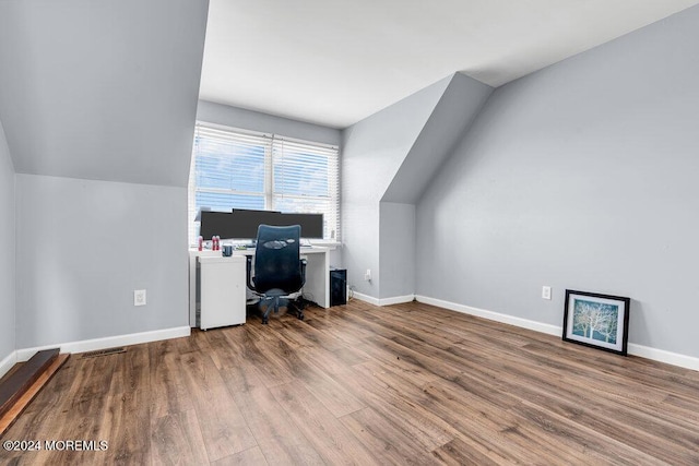 unfurnished office with baseboards, lofted ceiling, wood finished floors, and visible vents