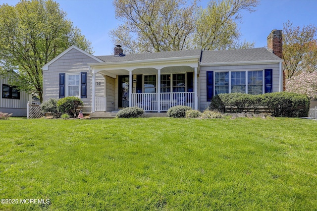 view of front of property with covered porch, a chimney, and a front lawn
