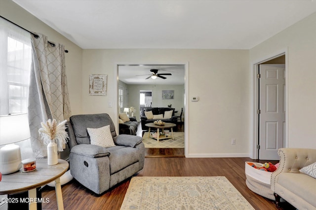 living room with baseboards, ceiling fan, and dark wood-type flooring