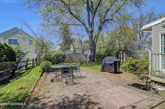 view of patio with an outdoor structure, a fenced backyard, a storage shed, and outdoor dining space