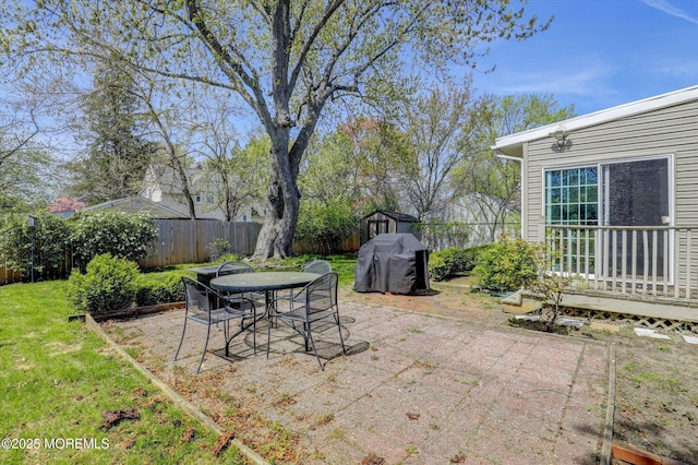 view of patio / terrace with an outbuilding, a fenced backyard, outdoor dining space, and a storage unit