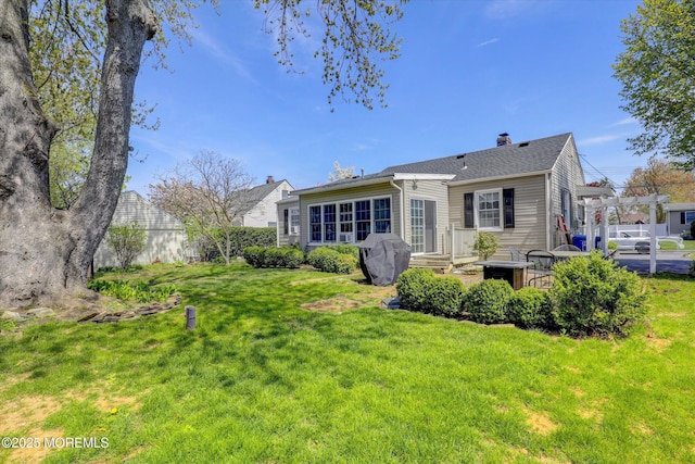 rear view of property with fence, a yard, and a chimney