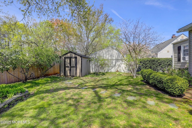 view of yard with a storage shed, fence, and an outbuilding