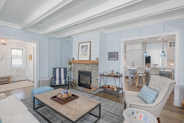 26 Bridge, Bay Head, NJ 08742 - living room featuring a decorative wall, wood finished floors, beamed ceiling, a stone fireplace, and ornamental molding