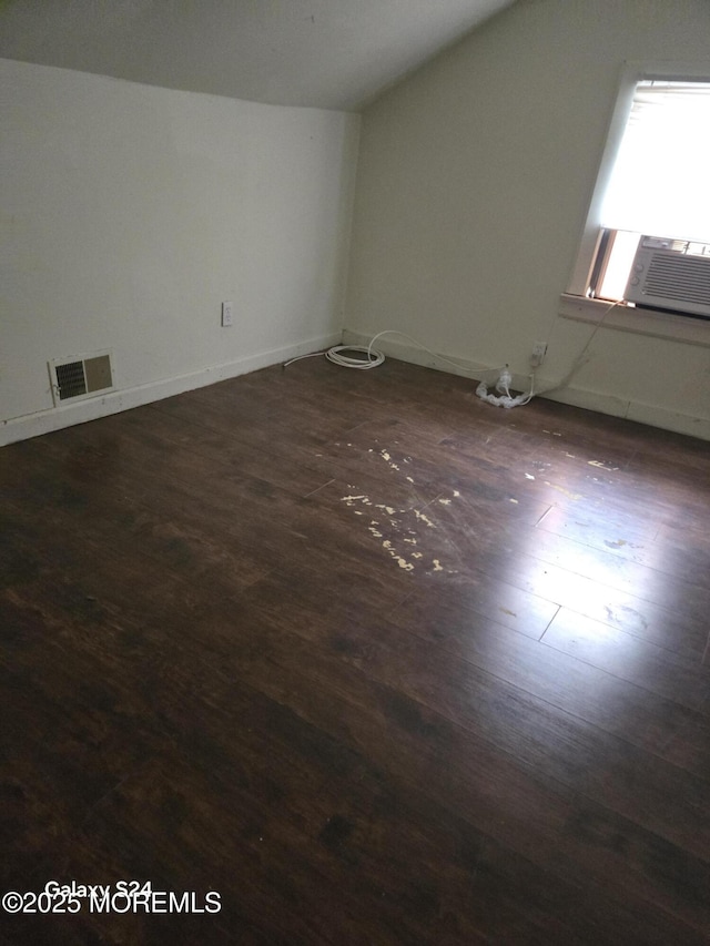 additional living space featuring visible vents, lofted ceiling, baseboards, dark wood-type flooring, and cooling unit