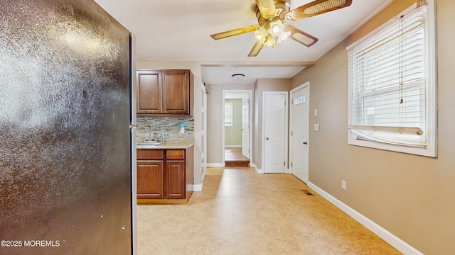 kitchen with a ceiling fan, visible vents, brown cabinets, a sink, and baseboards