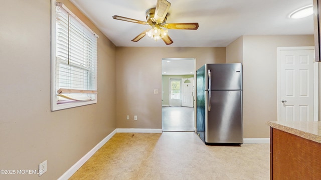 kitchen with freestanding refrigerator, baseboards, ceiling fan, and light countertops