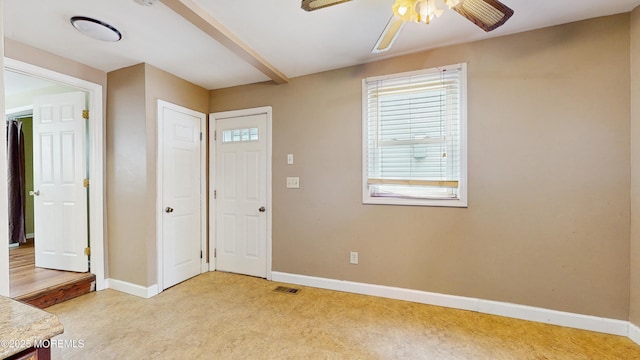 foyer featuring baseboards, ceiling fan, light carpet, and visible vents