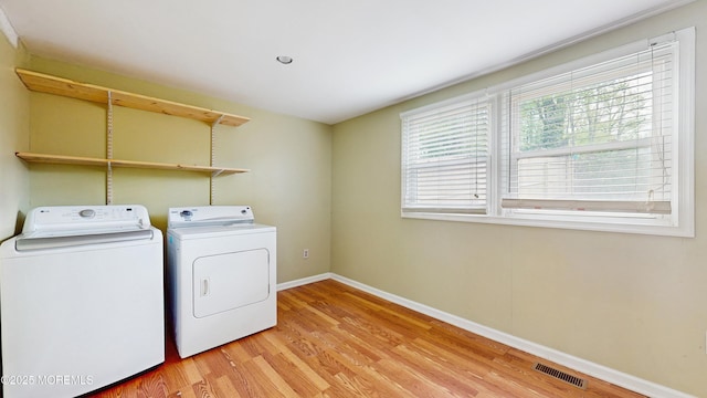 washroom featuring laundry area, visible vents, baseboards, washer and clothes dryer, and light wood finished floors