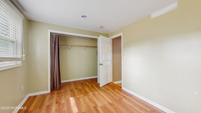 unfurnished bedroom with a closet, light wood finished floors, and baseboards