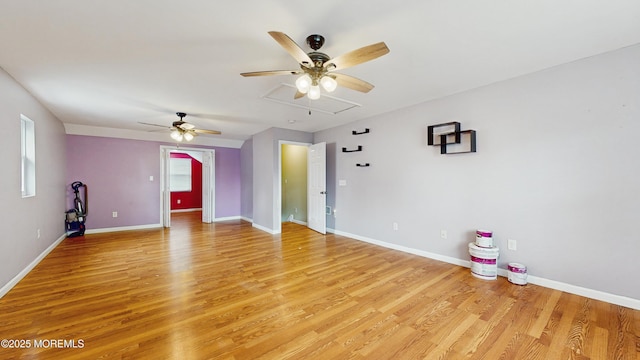unfurnished living room with a ceiling fan, baseboards, light wood-style flooring, and attic access