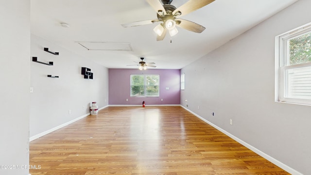 empty room with light wood-type flooring, a ceiling fan, and baseboards