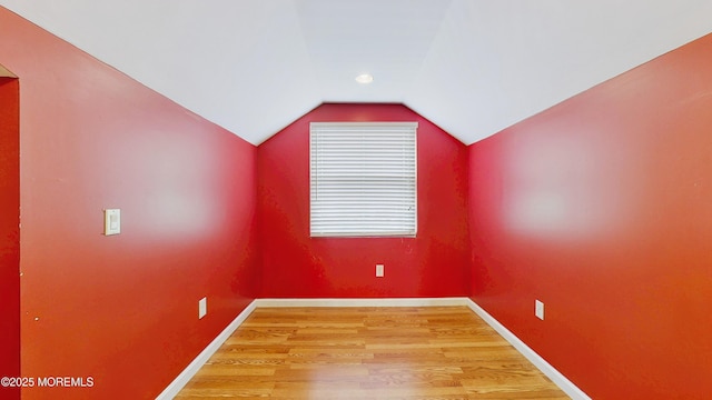 additional living space featuring baseboards, lofted ceiling, and light wood finished floors