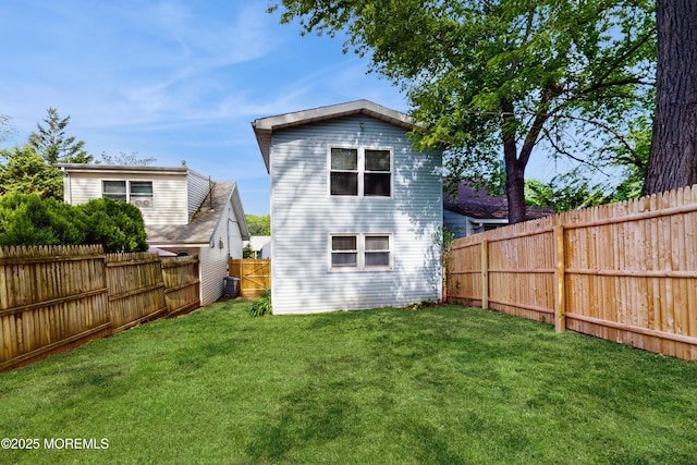 rear view of house featuring a lawn and a fenced backyard